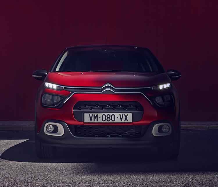 Citroen C3 червоного кольору, вигляд спереду з увімкненими приладами освітлення